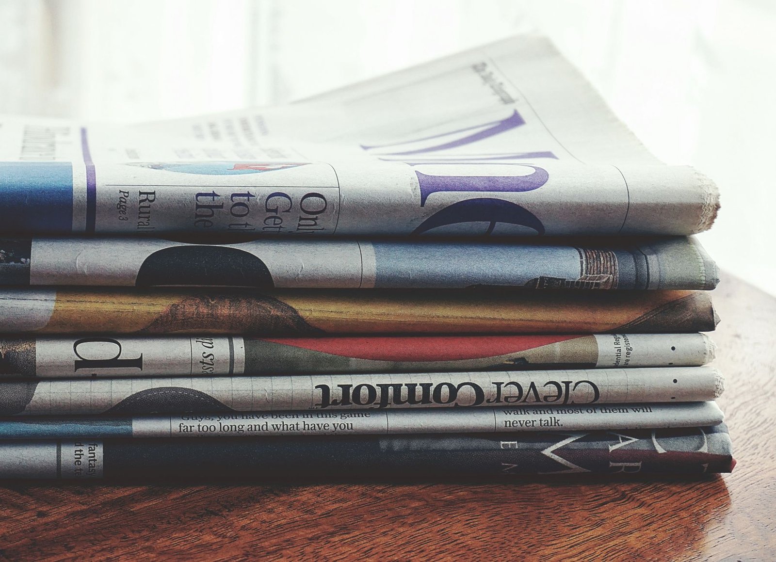 Publicaciones editoriales en varios idiomas europeos apiladas sobre mesa de madera